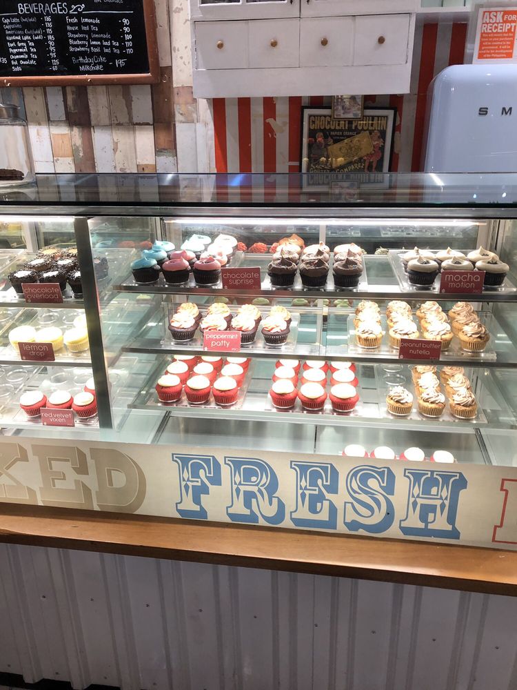 Baked Fresh Daily - cupcake display with red velvet, chocolate, and assorted flavors