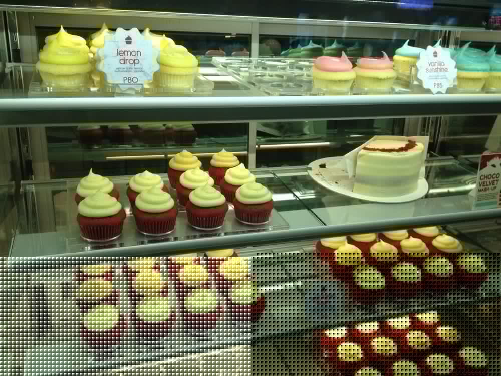 Red velvet cupcakes and lemon drop cupcakes with whole cake in display